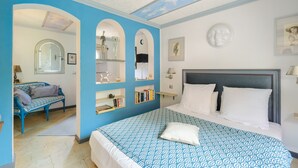 A bedroom with a bed, a blue and white patterned bedspread, a blue sofa, and built-in shelves with books and decorative items. - Room 'Serena' with Shared Terrace, Wi-Fi, and Air Conditioning (Menton)