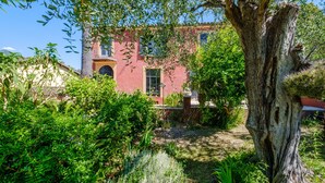 A red building with a large tree in the foreground, surrounded by lush greenery. - Room 'Serena' with Shared Terrace, Wi-Fi, and Air Conditioning (Menton)