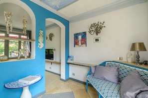 A room with a blue wall, a sofa, a table, and a TV.