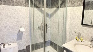 A modern bathroom with a glass-enclosed shower, a white toilet, a sink with a mirror, and marble tiles. - Wifaq Alnuzhah Hotel (Makkah)