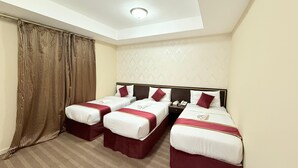 A hotel room with two single beds, a large window with curtains, a patterned wall, and a ceiling light. - Wifaq Alnuzhah Hotel (Makkah)