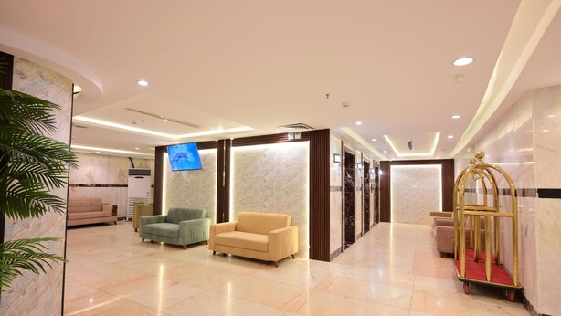 A hotel lobby with a reception desk, a television, and a gold-framed cart. - Wifaq Alnuzhah Hotel (Makkah)
