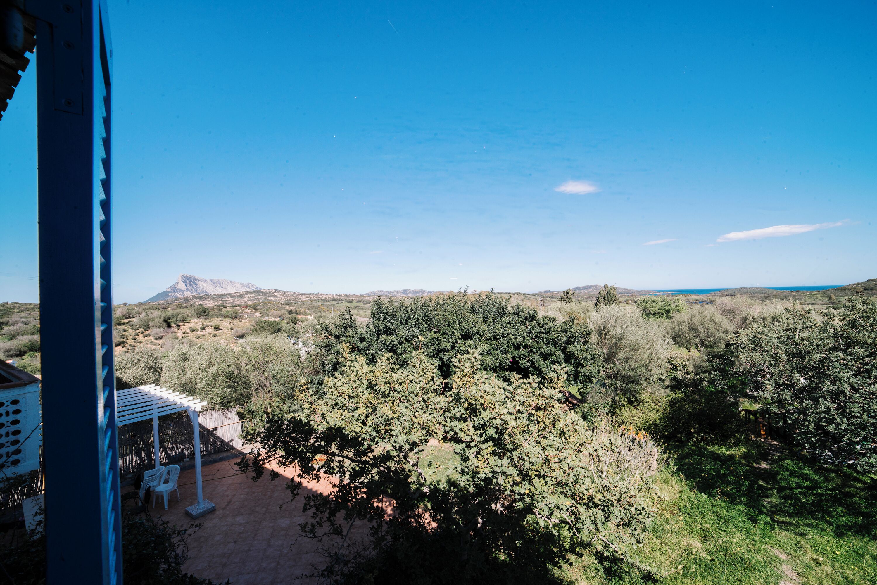 A patio area with a pergola, outdoor seating, and a view of a mountainous landscape.