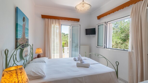 Un dormitorio con una cama, una lámpara, un cuadro, un televisor y vistas al verdor.