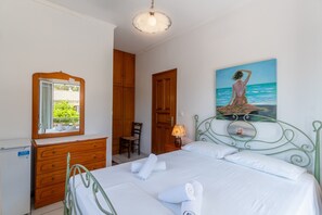 Une chambre à coucher avec un lit, une commode, un miroir, un tableau et une lampe.