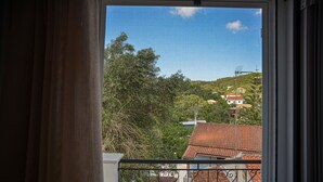 Una ventana con vistas a una zona residencial, con casas de tejas rojas y zonas verdes.