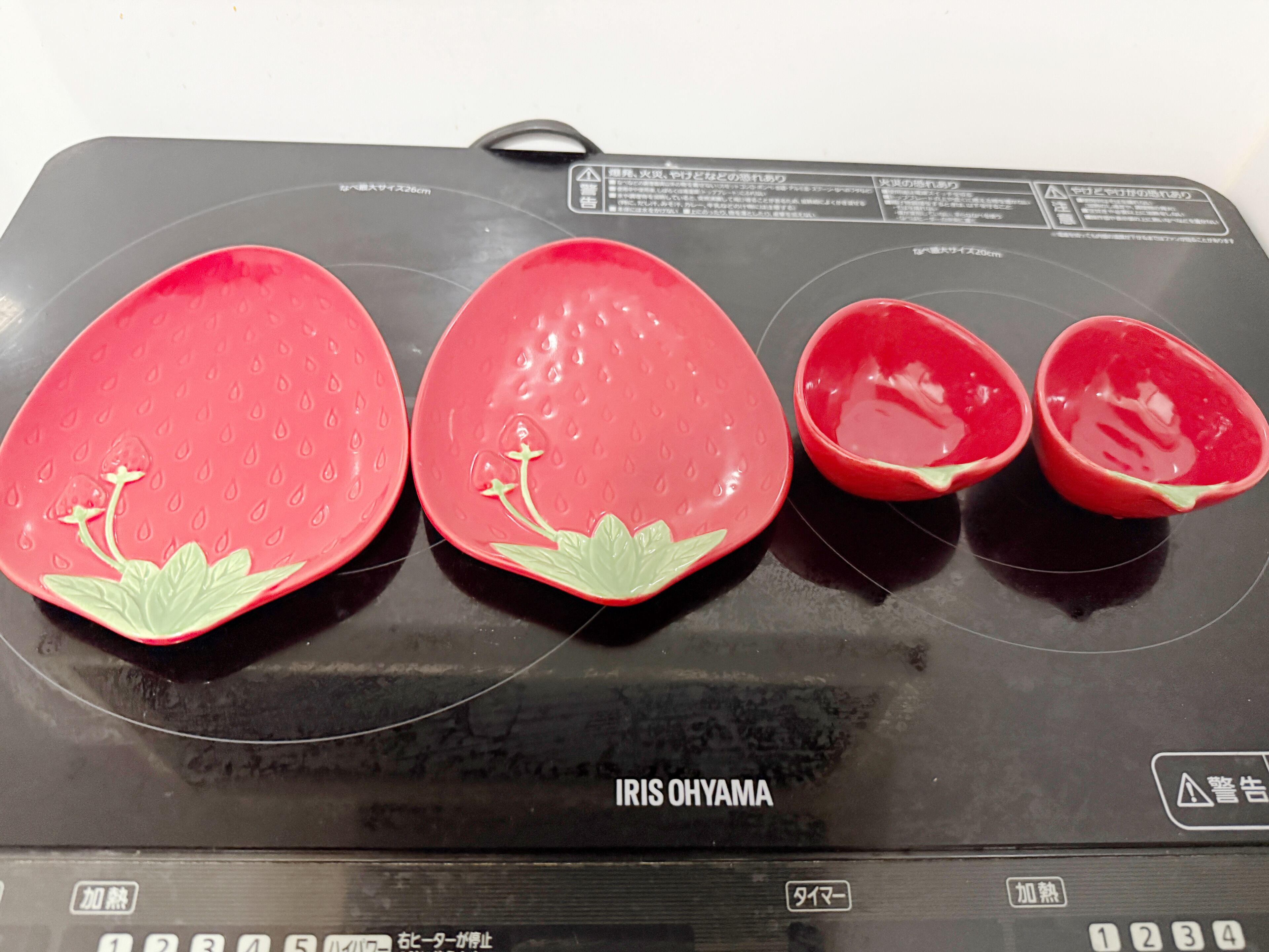 Une cuisine avec un plan de travail noir et trois assiettes rouges ornées de motifs verts.
