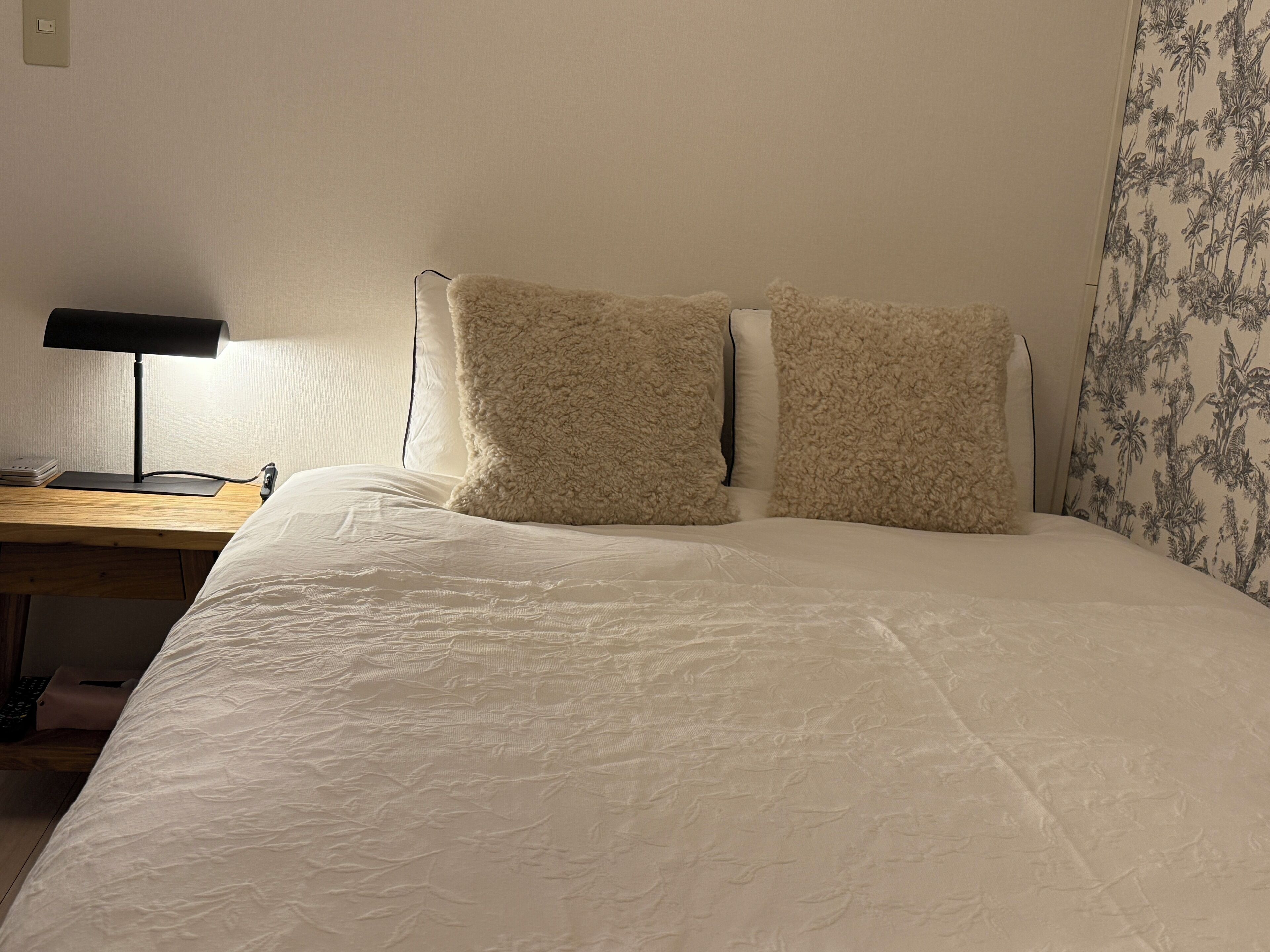 A neatly made bed with fluffy pillows and a wooden nightstand with a lamp.