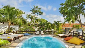 A swimming pool with lounge chairs and a wooden fence. - Flow House Jeri (Jijoca de Jericoacoara)
