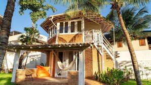 A two-story house with a balcony, a hammock, and a small patio area. - Flow House Jeri (Jijoca de Jericoacoara)