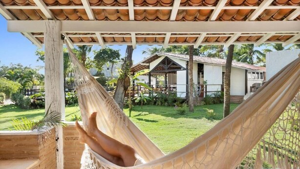 A hammock under a pergola with a view of a house and garden. - Flow House Jeri (Jijoca de Jericoacoara)