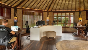 A reception area with a thatched roof, wooden walls, and a large window with a view of greenery. - Flow House Jeri (Jijoca de Jericoacoara)