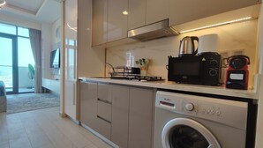 A modern kitchen with a built-in washer and dryer, a microwave, and a stove. - Lux BnB Farhad Azizi- Al Jaddaf  (Dubai)