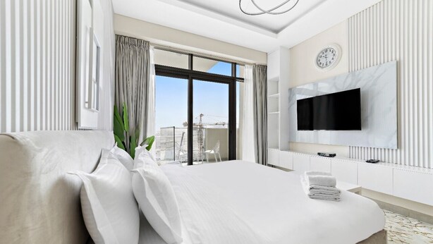 A modern hotel room with a large bed, a flat-screen TV, a balcony with a view, and a large window with curtains. - Lux BnB Farhad Azizi- Al Jaddaf  (Dubai)
