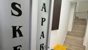 A hallway with a door labeled "APART" and a yellow trash bin to the right. - İSKELE APART AVŞA  (Marmara)