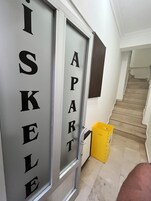 A hallway with a door labeled "APART" and a yellow trash bin to the right.