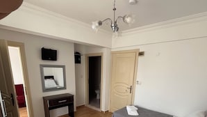 A hotel room with two beds, a desk, a mirror, and a chandelier. - İSKELE APART AVŞA  (Marmara)