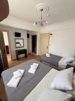 Ein Hotelzimmer mit zwei Betten, einem Schreibtisch, einem Spiegel und einer Kristallleuchtre.'