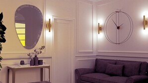 Una habitación con un espejo redondo, un reloj de pared circular, un sofá y una mesita con adornos.