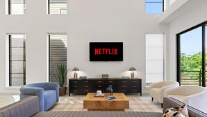 A modern living room with a large TV displaying 'NETFLIX', a black entertainment unit, a wooden coffee table, and two sofas. - Ultimate Group Getaway - Twin Lofts - Sleeps 20 (Dallas)