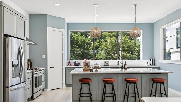 A modern kitchen with a large island, stainless steel appliances, and a view of trees through a large window. - Ultimate Group Getaway - Twin Lofts - Sleeps 20 (Dallas)