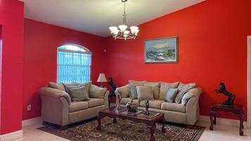 A living room with two beige sofas, a coffee table, and a chandelier.