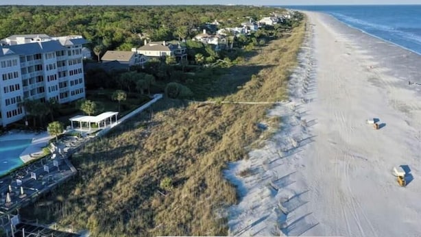 Et kysthotel med udsigt til stranden, en swimmingpool og en vej ned til stranden.