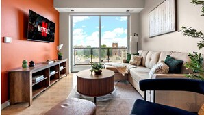 A modern living room with a large TV, a sofa, a coffee table, and a view through a large window. - Stylish 1B in DT Minneapolis, Minutes to Minneapolis Convention Center & US Bank (Minneapolis)