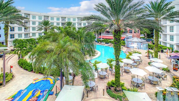 Un hotel con piscina, mobiliario exterior y palmeras.