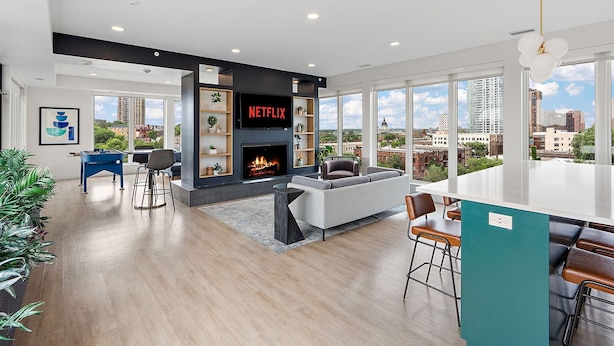 Una sala de estar moderna con chimenea, televisor con Netflix y vistas a la ciudad.