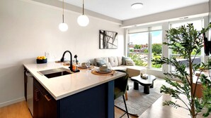 Una cocina moderna con una isla central, un área de comedor con sofá y un amplio ventanal con vistas a la ciudad.