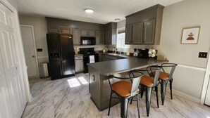 Una cocina moderna con una isla central, taburetes de bar y electrodomésticos integrados.