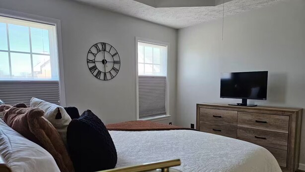 Un dormitorio con una cama, un reloj, un televisor y un aparador.