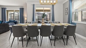 A dining area with a rectangular table set for six, surrounded by grey chairs.