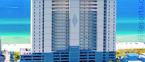 Un hotel moderno de gran altura con varios pisos, una estructura vertical prominente y un garaje.