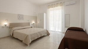 Un dormitori amb llit, abacines, un armari i una finestra amb cortines.