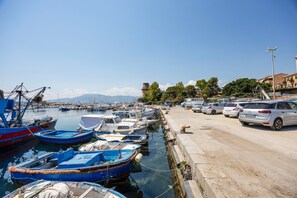 A marina with boats docked, a road with parked cars, and buildings in the background. - Holiday Home 'Sandovalli' with Sea View, Wi-Fi and Air Conditioning (Palermo)