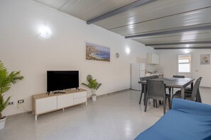 A living room with a TV, dining table, chairs, and a sofa. - Holiday Home 'Sandovalli' with Sea View, Wi-Fi and Air Conditioning (Palermo)