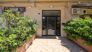 Entrada d'un edifici amb un cartell que diu 'SNAI SALA VLT' i una porta amb panells de vidre.
