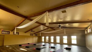 Une pièce spacieuse avec un plafond haut, des poutres en bois et de grandes fenêtres.