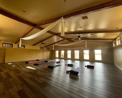 Una habitación amplia con techo alto, vigas de madera y ventanas grandes.
