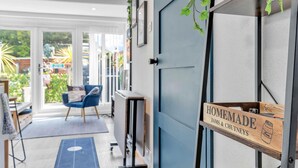 A modern kitchen with a built-in oven, a blue chair, and a sign indicating homemade jams and chutneys. - Garden Room With Parking | By My Getaways (Lancing)