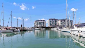 Een jachthaven met meerdere boten afgemeerd, een heldere lucht en gebouwen op de achtergrond.