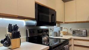Une cuisine moderne avec un micro-ondes noir, une cuisinière en acier inoxydable et un grille-pain.