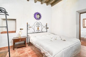 A bedroom with a bed, a nightstand, a wall-mounted mirror, and a window.