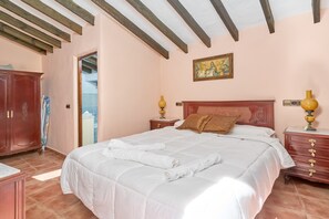 Quarto com cama, cabeceira de madeira, mesas de cabeceira, guarda-roupa e um quadro na parede.