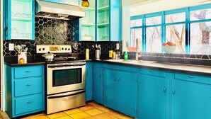 Une cuisine avec des meubles de couleur bleue, une cuisinière, un four et une fenêtre donnant sur des arbres.