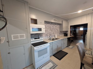 A kitchen with a microwave, stove, sink, and cabinets.