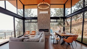 Una sala de estar moderna con un amplio sofá seccional gris, piso de madera y una chimenea de piedra.