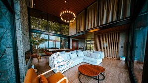 Un salón espacioso con un sofá modular grande, suelo de madera y una lámpara de araña moderna.